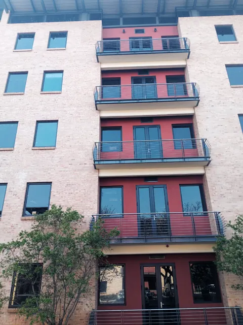 Brick and red-plaster apartment block with dark steel balconies after repainting
