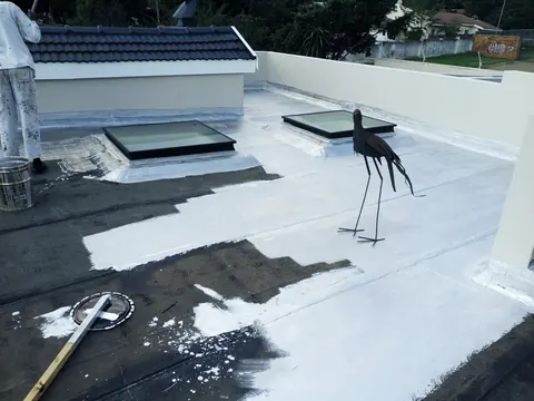 Flat roof being sealed with white liquid membrane waterproofing