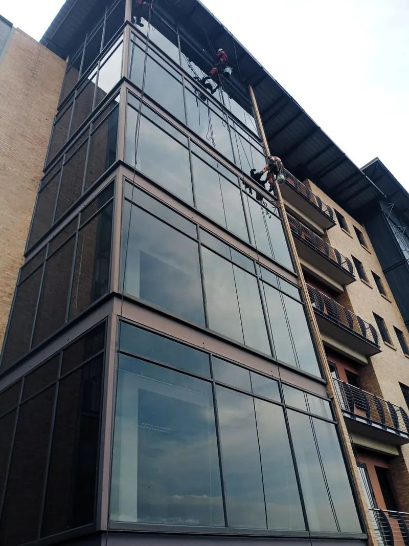 Looking up a glass corner tower with two MP technicians on ropes near the top